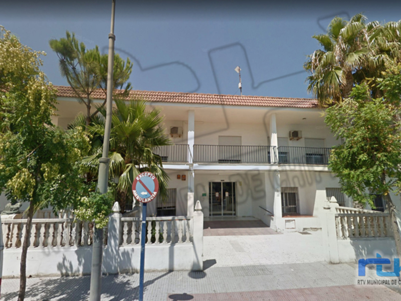 Edificio blanco con balcones y árboles alrededor, ubicado en Chipiona, España.
