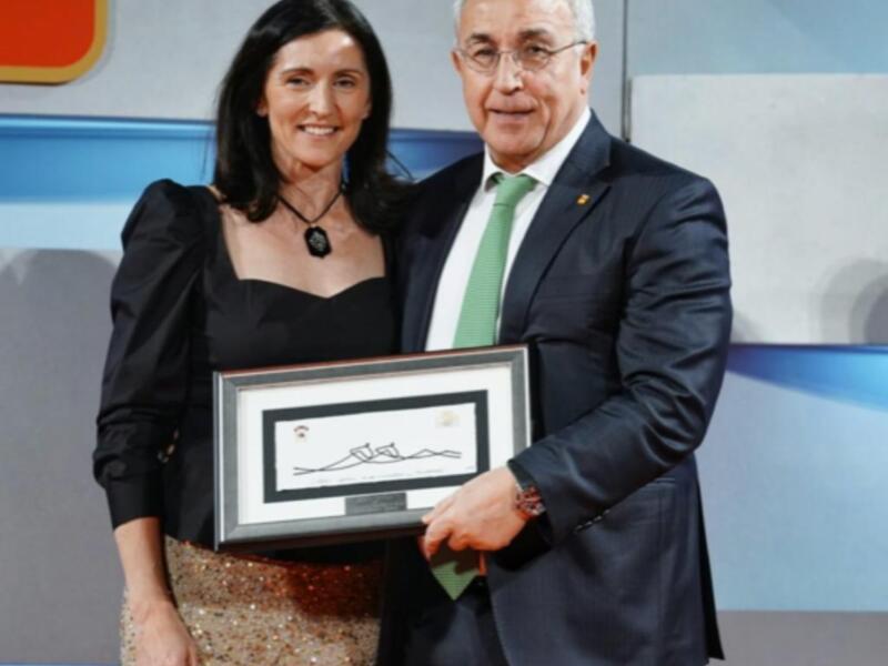 Una mujer recibe un reconocimiento de manos de un hombre en un evento formal.