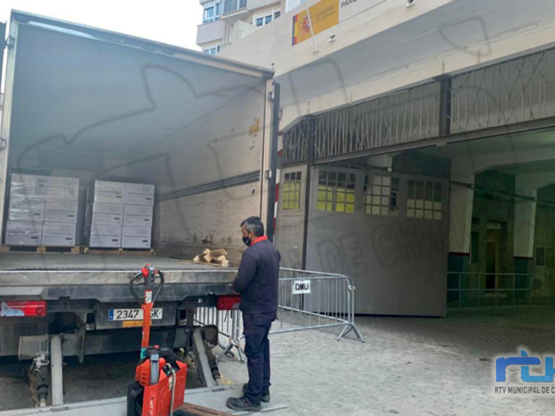 Traslado de mercancías en un camión grande frente a un edificio administrativo en Chipiona.
