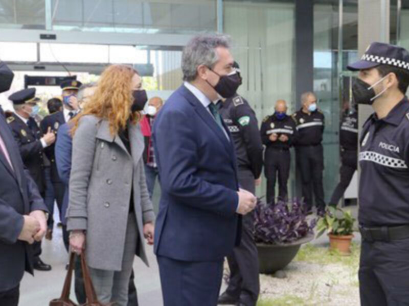 Oficiales de policía conversan con autoridades en un evento público, con máscaras y distanciamiento social.