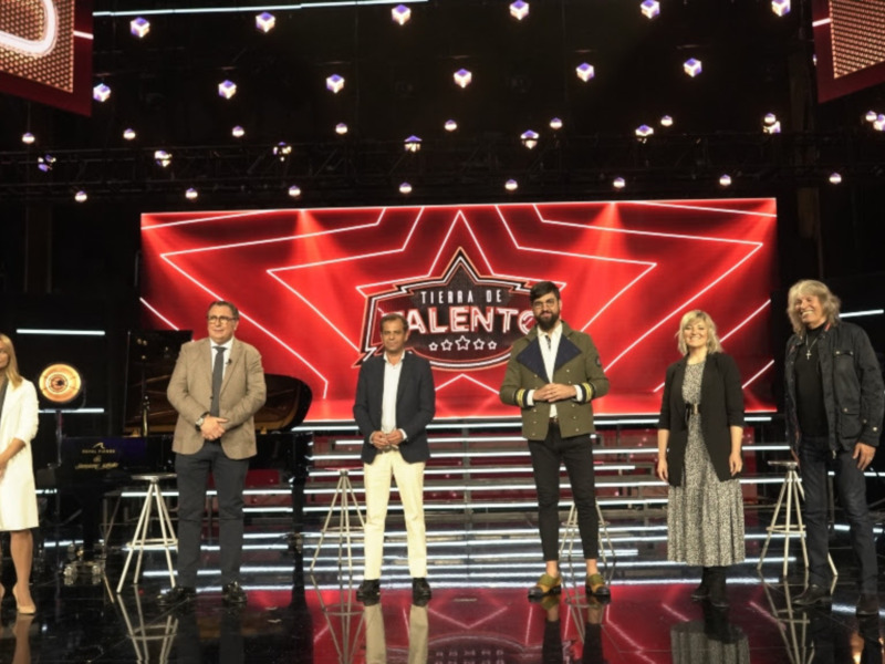 Júri y panel de 'Tierra de Talento' en un escenario con luces y un piano en el fondo.