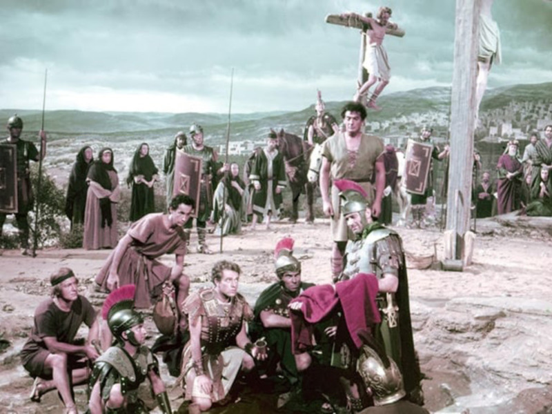 Escena histórica con soldados romanos y figuras bíblicas en un paisaje desértico.