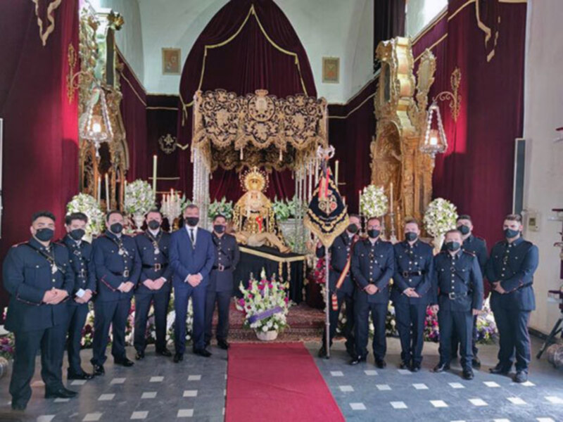 Oficiales y autoridades en una ceremonia religiosa en un templo decorado con flores y altares.