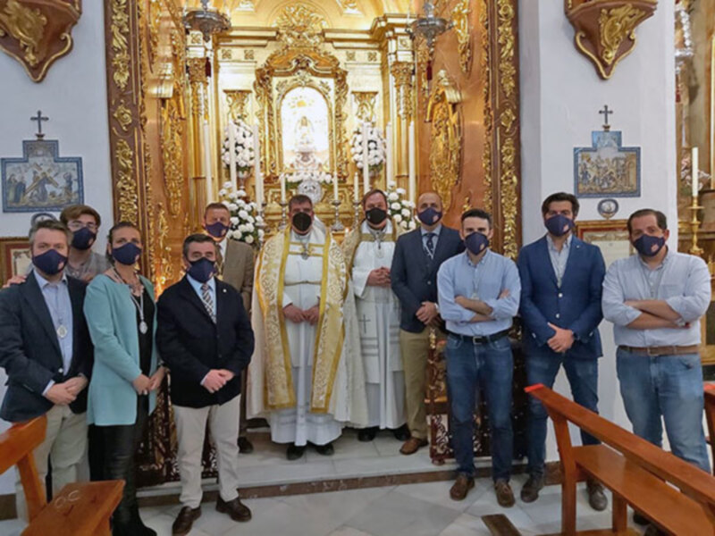Celebración religiosa en un templo con un sacerdote y un grupo de personas con máscaras faciales.