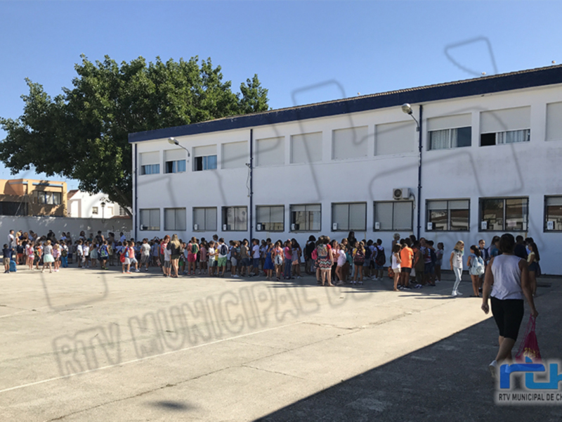 Estudiantes y profesores reunidos en el patio de una escuela municipal.
