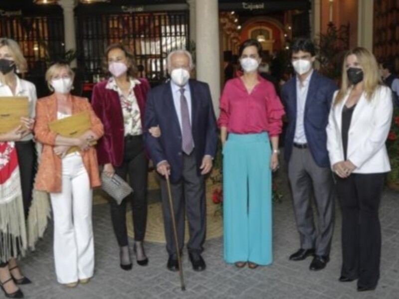Una reunión formal con personas vestidas formalmente, algunas con máscaras faciales, posiblemente en un evento o conferencia de negocios.