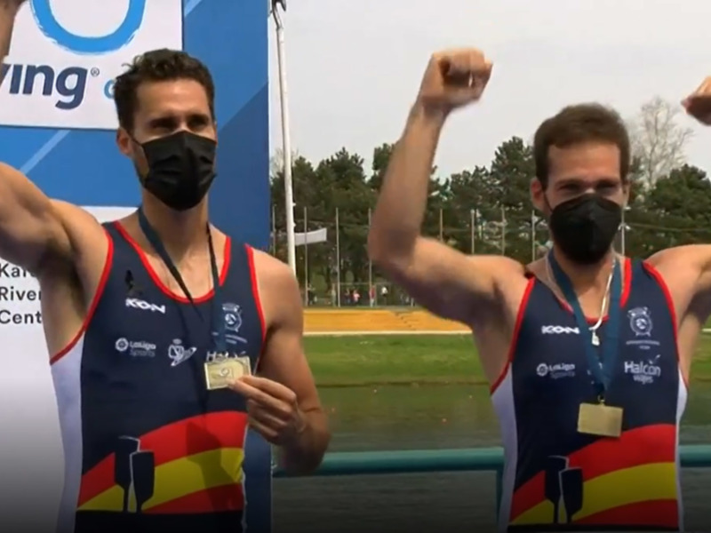 Atletas celebran su victoria en el podio, luciendo medallas y mascarillas, tras una competición de remo.