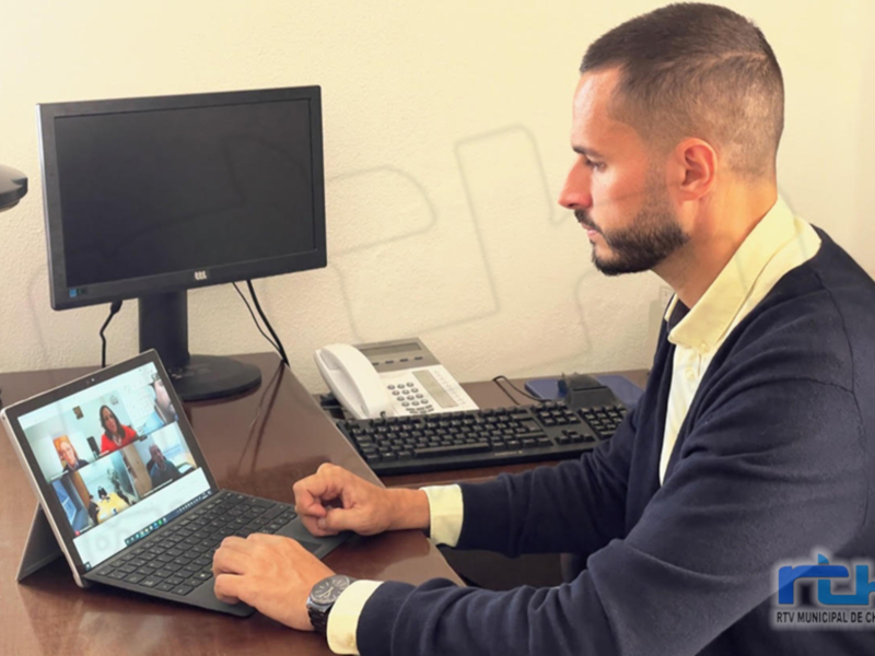 Persona participando en una reunión virtual en una oficina.