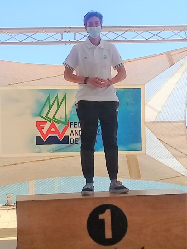 Un joven con una máscara facial y ropa deportiva, posando en un podio con el número 1, en un contexto de competición o ceremonia.