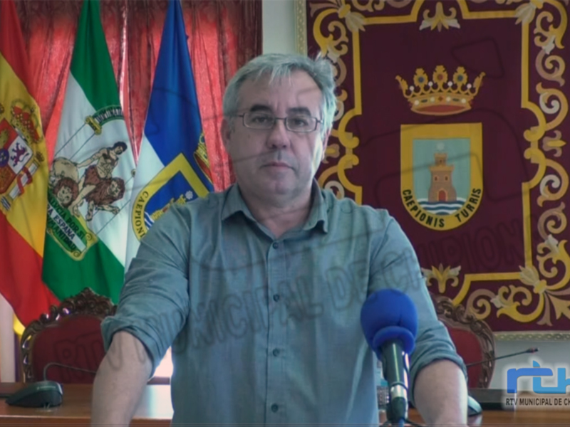 Entrevista en el Ayuntamiento de Chipiona, con banderas y escudo municipal en el fondo.