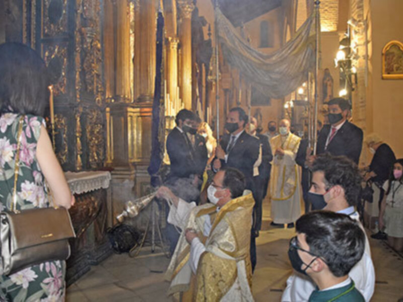 Celebración religiosa en una iglesia adornada, con sacerdotes y fieles participando en una ceremonia con incienso.