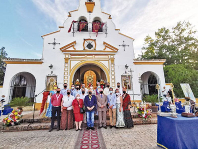 Celebración en la ermita de Santa Ana, con personas vestidas tradicionalmente y ofrendas florales.