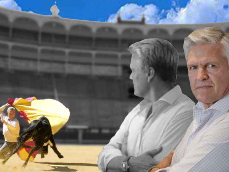 Un torero en acción en una plaza de toros, con dos hombres observando serios en primer plano.