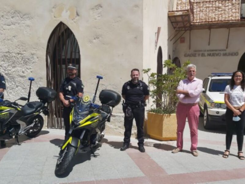 Policías y autoridades posan junto a motocicletas y un vehículo de policía en un entorno urbano.