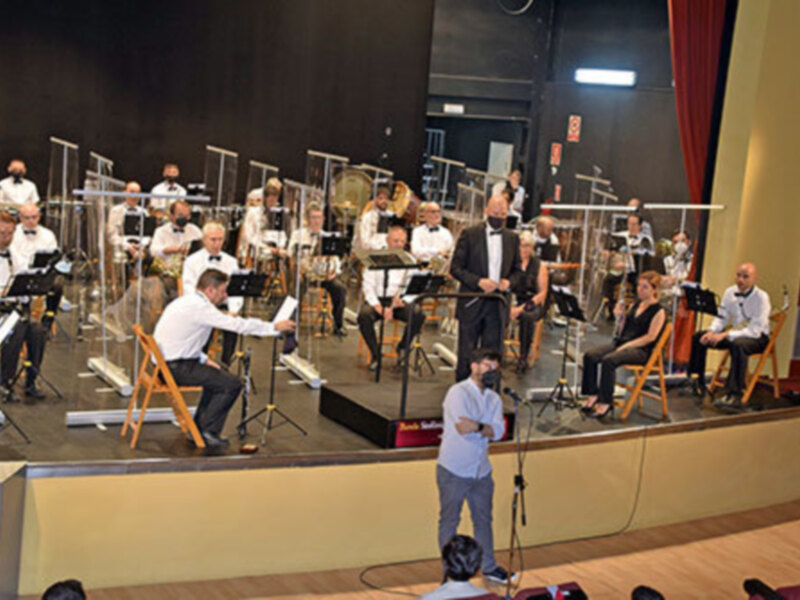 Orquesta sinfónica en un concierto, con músicos tomando notas y un director al frente.