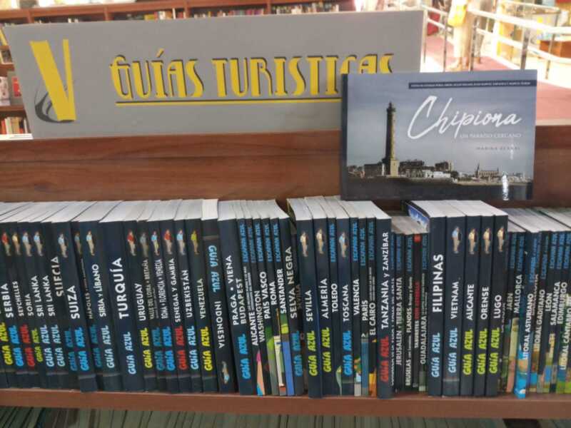Libros de guías turísticas en una biblioteca, con una guía específica sobre Chipiona en la parte superior derecha.