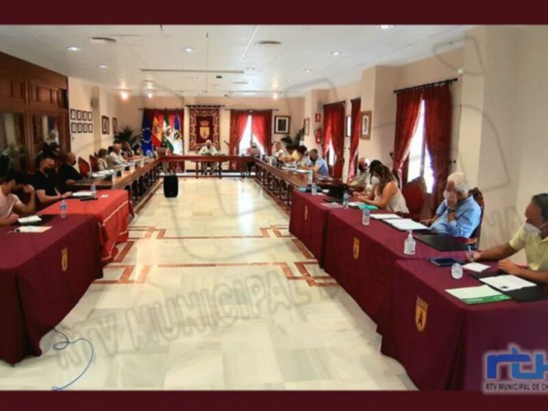 Reunión en el salón de plenos del Ayuntamiento de Chipiona, con participantes sentados alrededor de una larga mesa.