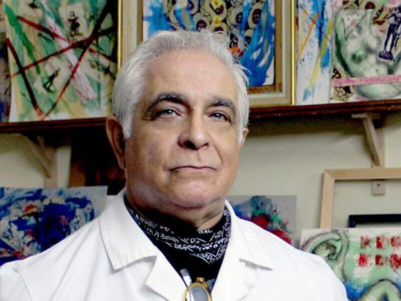 Retrato de un hombre en un estudio de arte, rodeado de obras de arte abstractas.