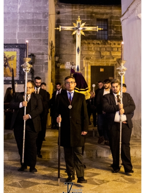 Procesión religiosa nocturna con portadores de cruces y palmas en una iglesia histórica.