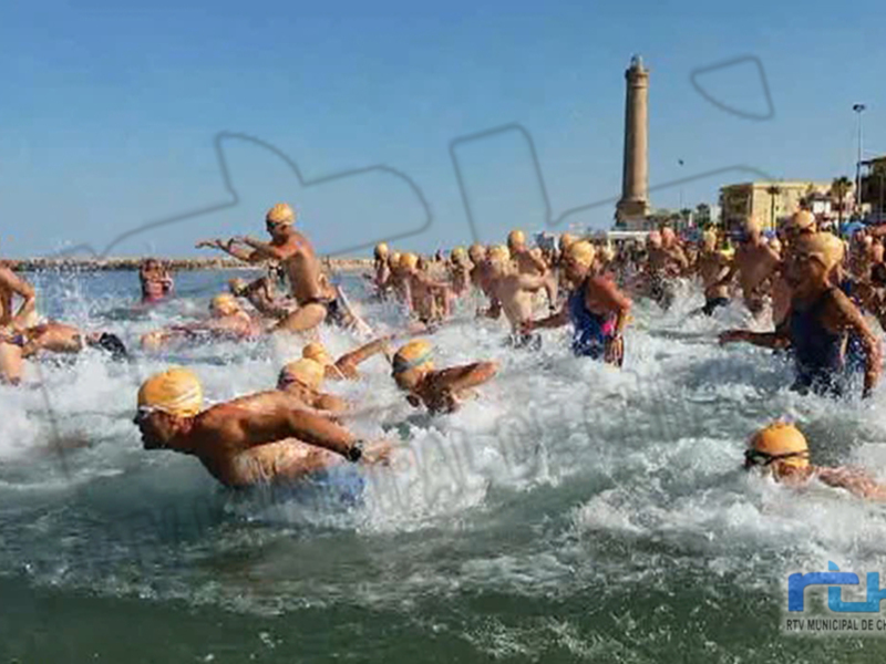 Competencia de natación en el mar, con nadadores desafiando las olas y el viento en un entorno urbano.