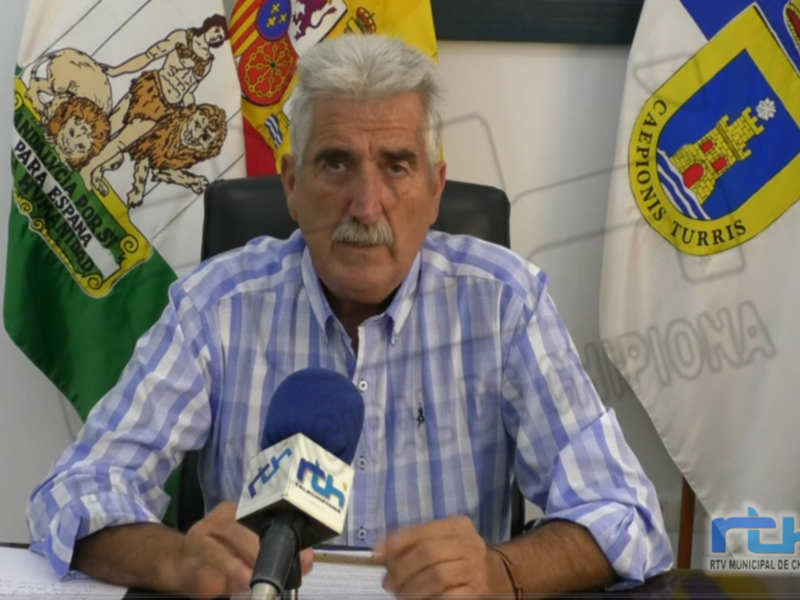 Entrevista de un político en un despacho, con banderas nacionales en el fondo.