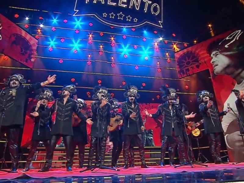 Grupo musical en escenario con luces y fondo de estrellas, actuando en un evento de talento.