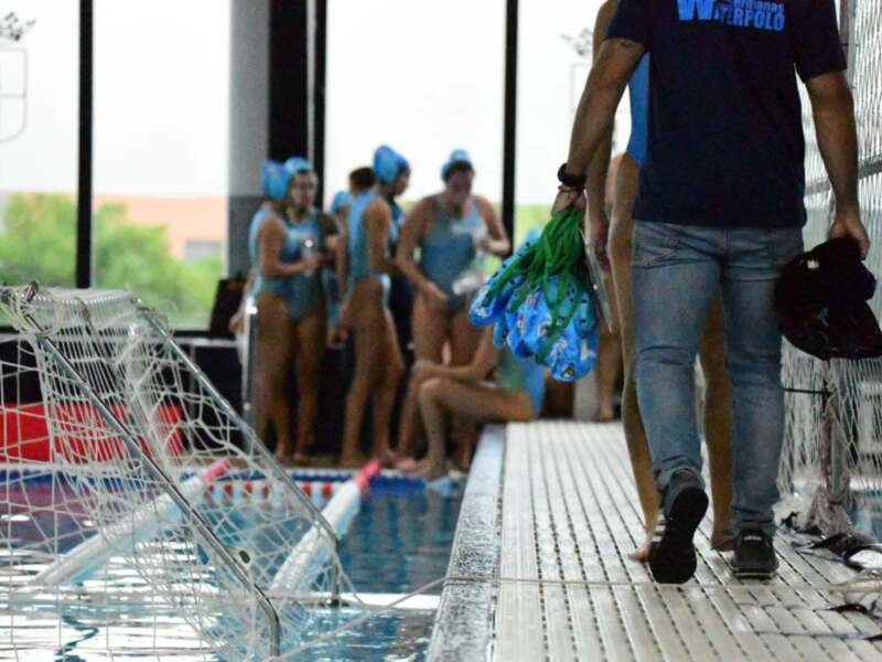 Swimmers preparing for a water polo match in an indoor pool.