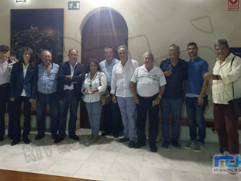 Gruppo di persone in posa per una foto di gruppo all'interno di un edificio con un dipinto sullo sfondo.