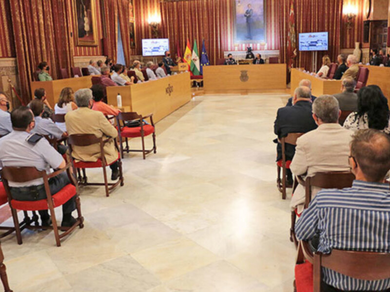 Reunión en una sala de conferencias con varias personas sentadas en filas, mirando hacia el frente.