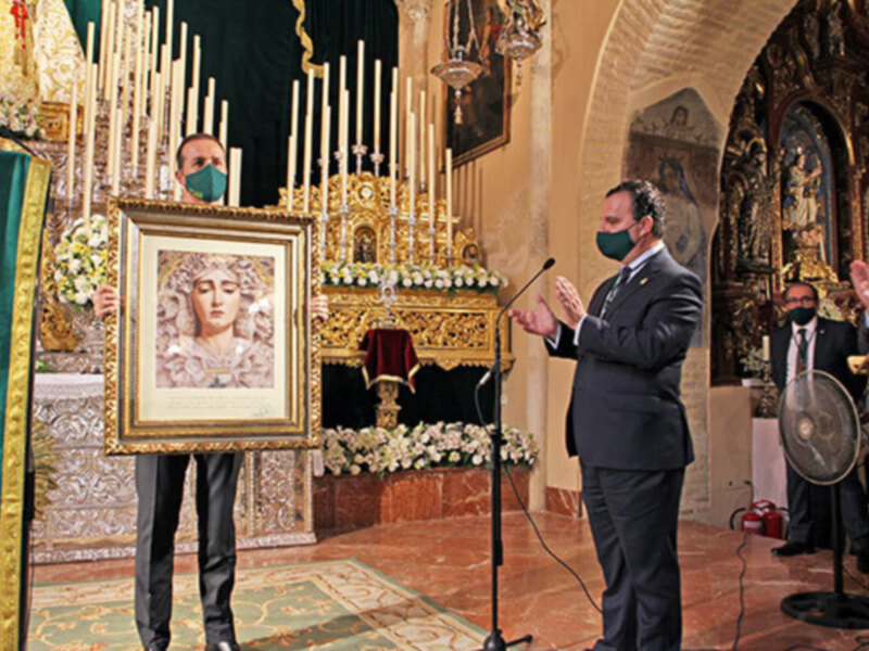 Celebración religiosa en una iglesia con un hombre hablando en un micrófono y otra persona sosteniendo un cuadro de la Virgen María.