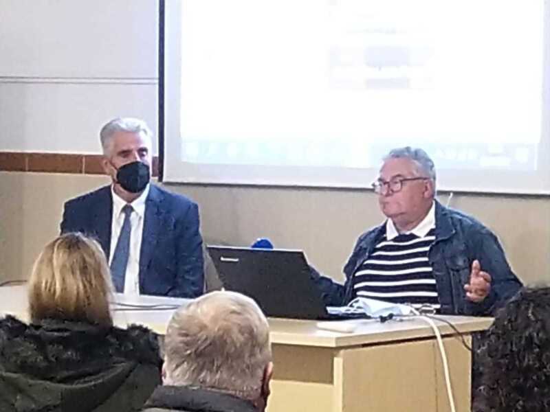 Hombre hablando en un seminario o conferencia, con audiencia en primer plano.
