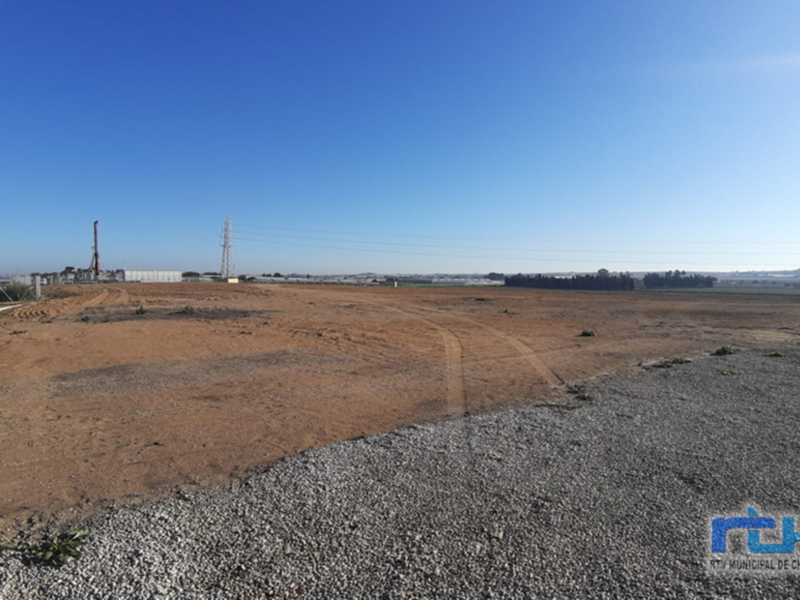 Imaginación de un futuro parque eólico en el campo, con torres de energía y un paisaje despejado. El cielo azul y la extensión del terreno sin vegetación sugieren una zona ideal para la instalación de infraestructuras eólicas.
