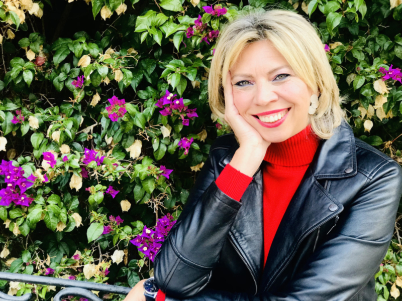Retrato de mujer sonriente con chaqueta de cuero y fondo de flores moradas