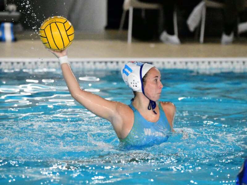 Jugadora de waterpolo en acción, lanzando el balón en la piscina.
