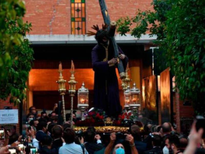 Procesión religiosa con imagen del Cristo de la Buena Muerte, rodeada de fieles y decoración floral.