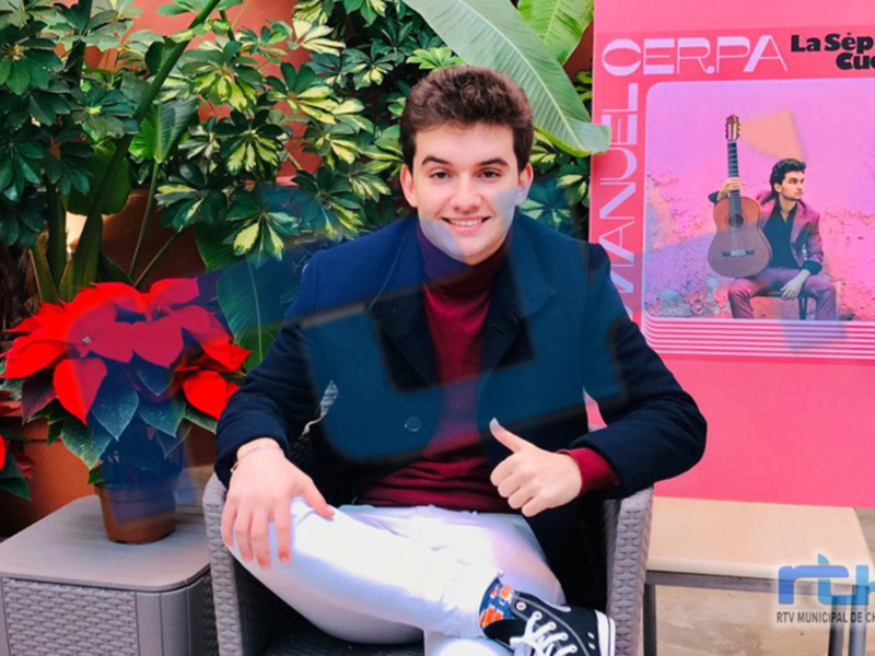 Artista promocionando su álbum 'La Séptima Cuerda' en un ambiente acogedor con plantas y flores rojas.