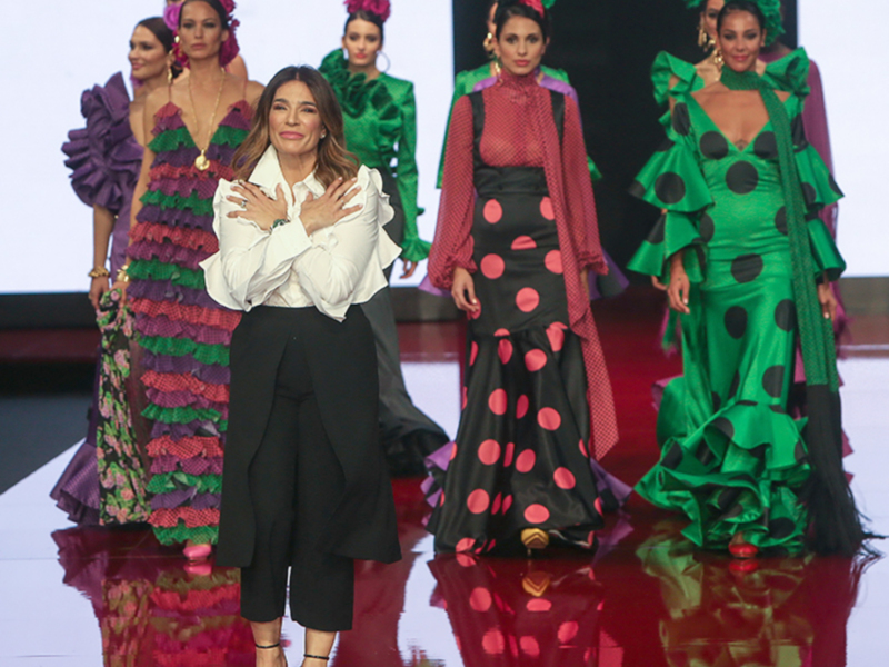 Desfile de moda flamenca con diseñadora y modelos en pasarela.