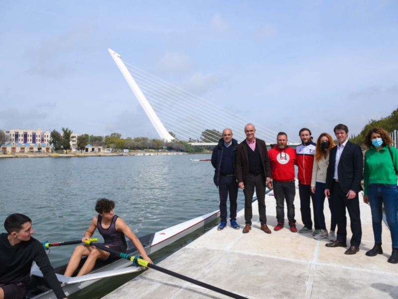 Equipo de remo posando en el muelle con el puente de la Salve al fondo.