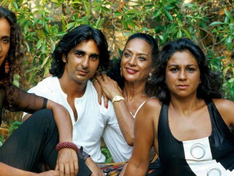 Una familia feliz en un entorno natural, con una madre y dos hijas sentadas juntas, rodeadas de vegetación.