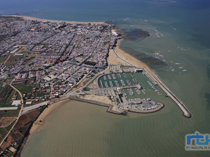 Vista aérea de Chipiona, mostrando la ciudad costera, el puerto marítimo y la extensión del litoral.