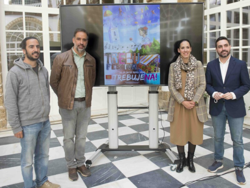 Tres personas posan frente a un televisor con un cartel de festival, con una fecha específica en abril de 2023. El evento se llama 'Trebu' y tiene un diseño colorido y festivo.