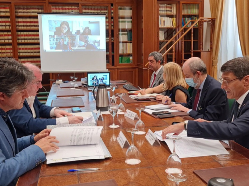 Reunión de trabajo en sala de conferencias con participación virtual.