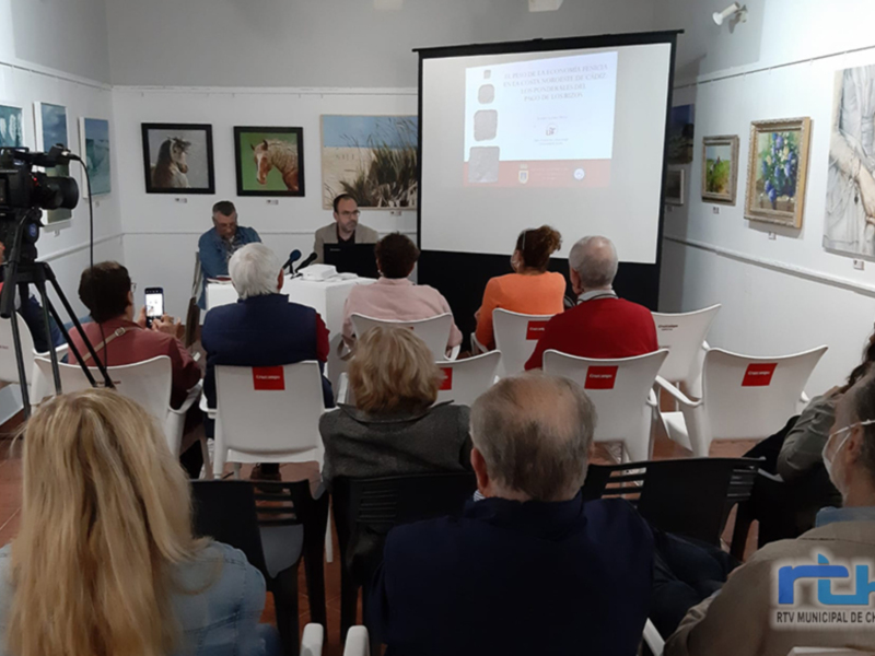 Presentación de un proyecto en el salón de actos municipal de Chipiona, con una pantalla proyectada y una mesa redonda en el centro.