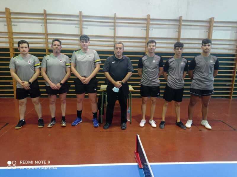 Equipo de tenis de mesa con su entrenador en una cancha de entrenamiento.