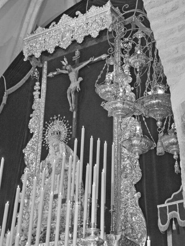 Procesión religiosa con estatuas de la Virgen y el Cristo en un altar adornado con candelabros y decoraciones doradas.