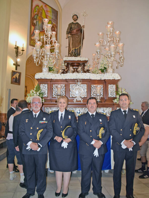 Cuatro personas en uniforme militar posan para una foto frente a una estatua religiosa y una candelabro en una iglesia. La escena parece ser una celebración o una ceremonia religiosa.