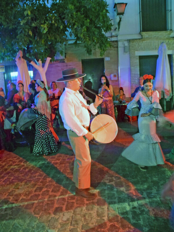 Fiesta tradicional con música y danza en la noche, con músicos y bailarinas vestidos de trajes típicos.