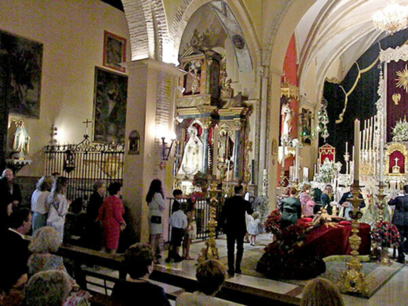 Interior de una iglesia con altares y flores en las mesas.