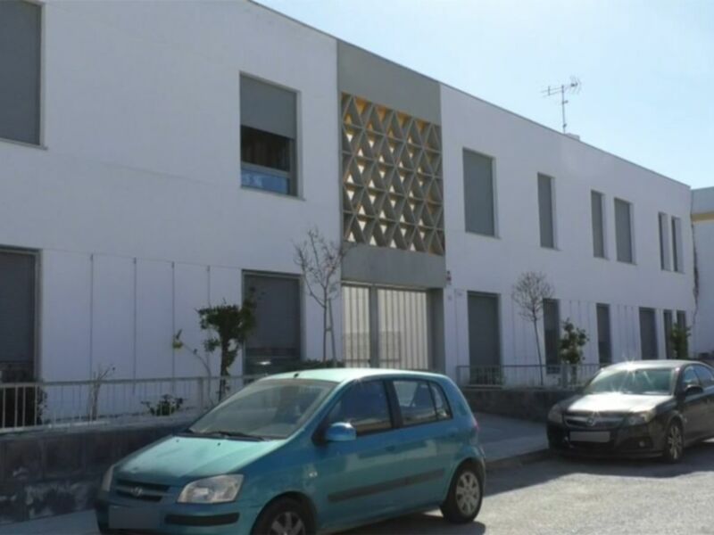 Edificio moderno con fachada blanca y diseño geométrico en la entrada.