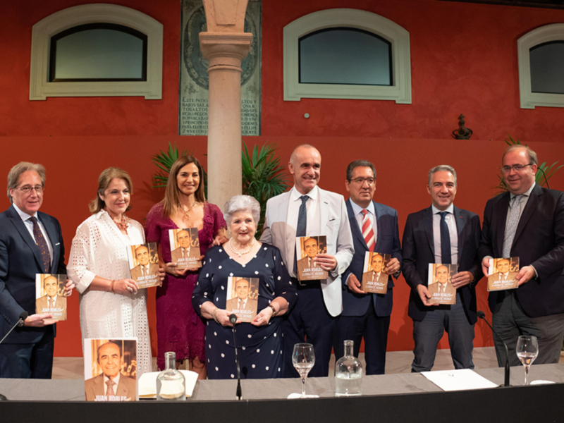 Presentación del libro 'Juan Roig' en un evento formal en un salón con decoración clásica.